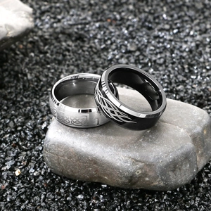 Close-up of Celtic knot and flame patterns on silver and black tungsten rings for men