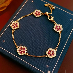Detailed close-up of 18k gold plated flower bracelet with red gems and white zircons