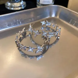 Silver hoop earrings with butterfly charms and shimmering rhinestones on a metal tray