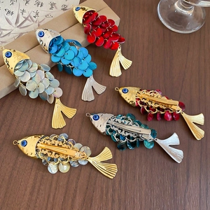 Detailed macro view of fish-shaped hair clips with shimmering sequins and metal finish