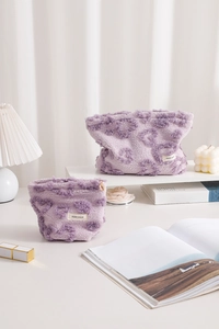 Detail of purple faux fur makeup bags with embossed heart patterns and metallic zipper