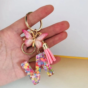 Close-up of resin letter N keychain with pink butterfly, tassel and heart sequins