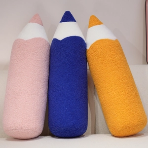 Soft creative pencil plush pillows in pink, blue, and orange on a modern sofa