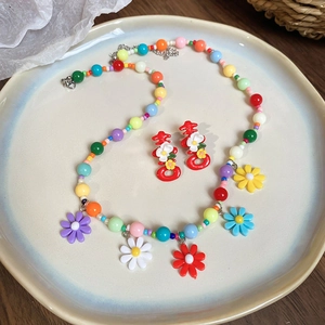 Detail of colorful beaded necklace with floral pendants and red festive earrings