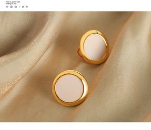 Detail of round gold-plated geometric earrings on gold silk fabric background