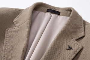 Détail du tissu texturé marron du blazer avec revers à cran et broche métallique M