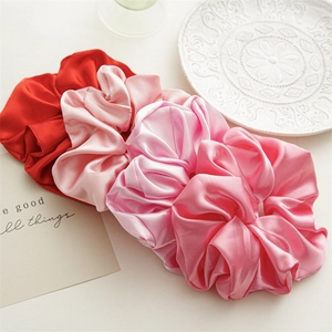 Detail showing oversized satin scrunchies in various shades of pink and red colors