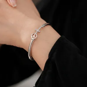Silver plated arrow cross bangle with sparkling crystals and peace sign charm for women