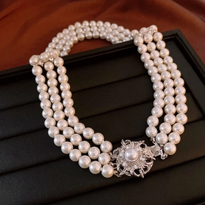 Close-up of triple-strand pearl necklace with a silver floral clasp on a jewelry tray