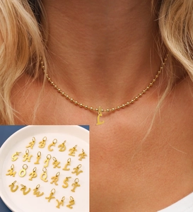 Detailed view of a gold stainless steel L-letter pendant necklace worn by a model