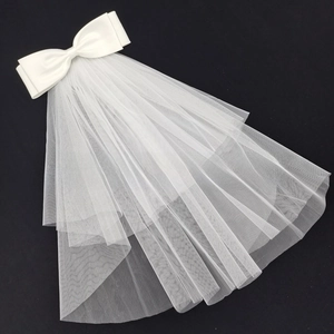 Detail of multi-layered white bridal veil with a large satin bow on a dark background