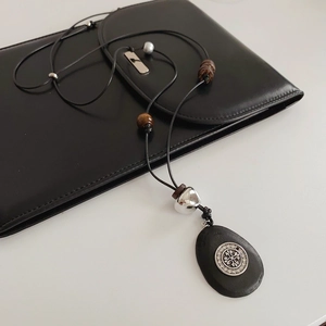 Détail d'un collier bohème avec pendentif en pierre noire et incrustation argentée sur blanc