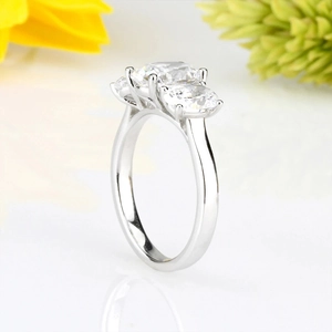 Vista macro lateral de elegante anillo de tres piedras con circonitas en banda de plata