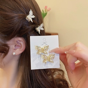 Detail of small butterfly hair clips with white pearls and crystals on gold alloy frame