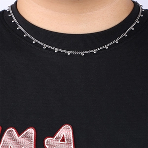 Close-up of a silver stainless steel beaded foot charm necklace worn on a model