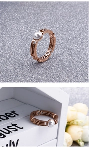 Detail of rose gold open geometric ring with white pearl on a decorative background