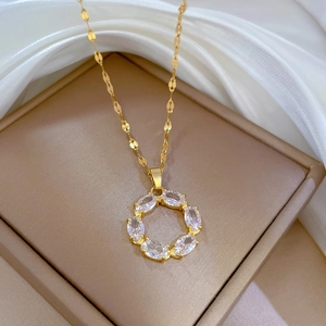 Minimalist gold titanium necklace with a round zircon pendant on white silk background