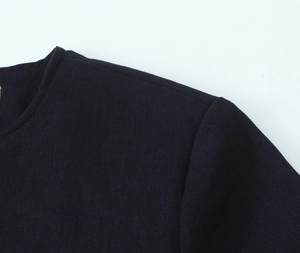 Detail of shoulder stitching and neckline on black buttoned suit jacket fabric