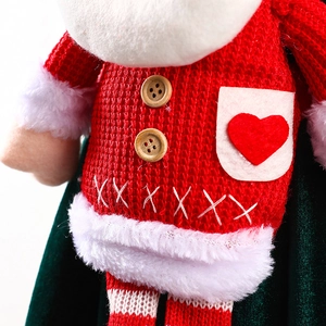 Gros plan de la poupée Père Noël avec texture tricotée rouge, boutons en bois et cape en velours