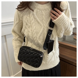 Detail of black quilted crossbody bag with adjustable wide strap and detachable mini pouch