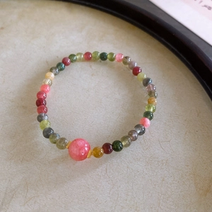 Macro shot of colorful Shoushan stone agate beaded bracelet with pink bead on beige paper