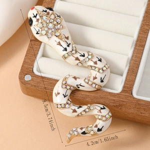 Close-up of snake brooch with white enamel, rhinestones, and 9.5cm x 4.2cm dimensions