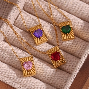 Macro shot of gold square pendants with heart-shaped zircon in four colors on velvet