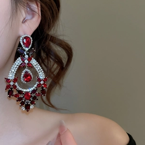 Close-up of elegant silver drop earrings with red crystal stones on a fashion model