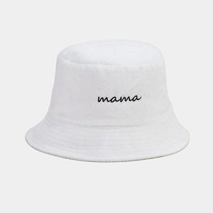 Dettaglio del ricamo nero 'mama' sul tessuto di spugna bianco di un cappello da pescatore