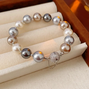 Detail of multicolored pearl bracelet with crystal magnetic clasp in a beige jewelry box