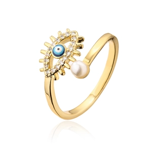 Macro detail of gold evil eye ring with blue enamel, zircon stones and white pearl