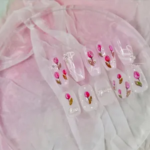 Detail of pink tulip press-on nails with hand-painted floral art and tiny pearls
