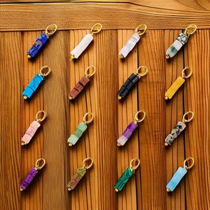 Variety of natural stone abacus bead pendants with gold rings on wood background