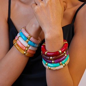 Gros plan de bracelets colorés en acrylique style bambou avec séparateurs dorés au poignet