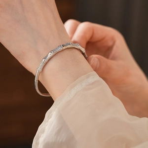 Macro shot of silver bamboo-style bangle with inlaid cubic zirconia on a model wrist