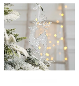 Close-up of glittery acrylic reindeer ornament hanging on a snowy branch with bokeh