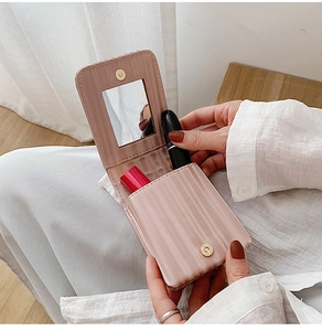 Pink purple leather lipstick bag with built-in mirror held by hand for easy makeup retouch