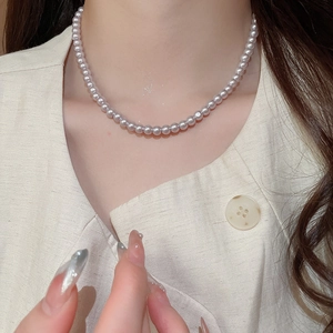 Close-up of elegant lavender pearl necklace on neck with minimalist beige linen shirt