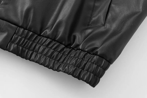 Detail of high-elasticity shirred hem and precise stitching on black faux leather bomber jacket