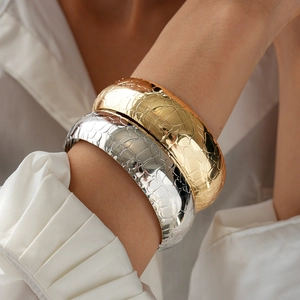Detailed view of wide metallic snake texture cuff bracelet with embossed crocodile pattern