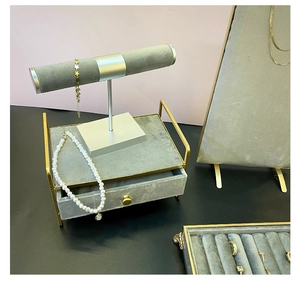 Detailed view of grey velvet jewelry display stand with golden metal frame and ring tray