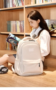 Minimalist beige nylon backpack placed next to a student in a cozy bookstore setting