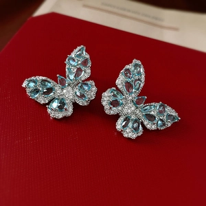 Detail of silver butterfly earrings featuring vibrant blue zircon gemstones on a red gift box