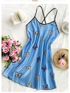 Detail of blue silk slip dress with butterfly print and black cross straps on fabric