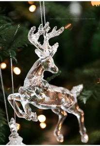 Macro detail of transparent acrylic reindeer ornament with white glitter on Christmas tree