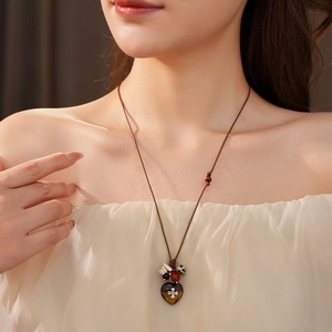 Detail of bohemian heart pendant necklace with brown cord and vintage metal flower motif