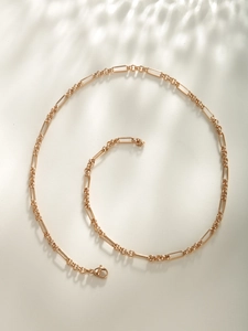 Detailed view of golden paperclip chain necklace with lobster clasp in a spiral layout