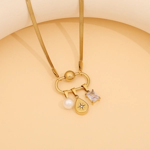 Detail of gold snake chain with pearl, star engraved pendant and zircon charms