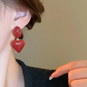 Close-up of red enamel heart drop earrings on model for a vintage elegant style