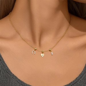 Detail of horseshoe heart and zircon charms on a gold minimalist necklace for women